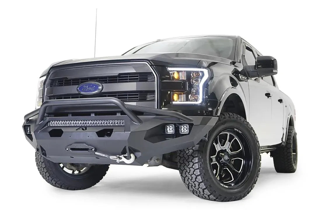 Fab Fours Matrix front bumper with pre-runner guard on a black Ford F-150, front driver-side three-quarter view, showing the pre-runner hoop, light bar and cube light pods