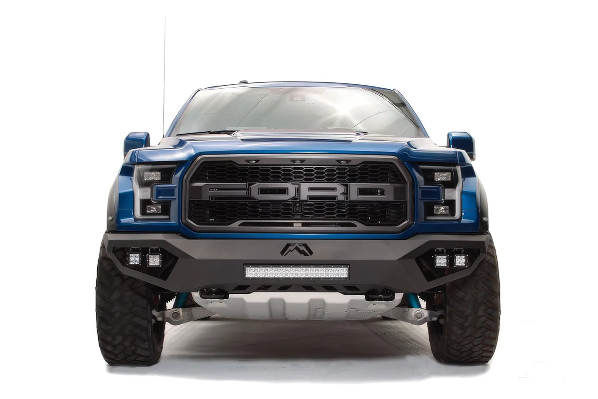 Fab Fours Vengeance front bumper on a blue and gray wrapped Ford Raptor, straight-on front view, showing the center light bar, cube light pods and Fab Fours logo