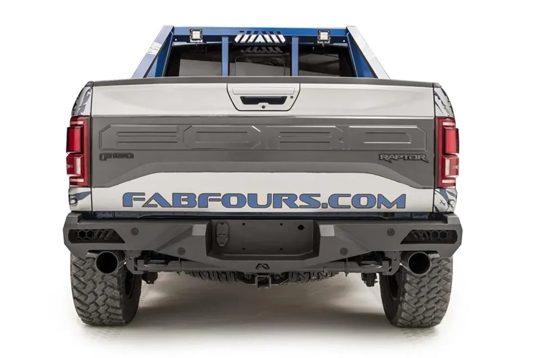 Fab Fours Vengeance rear bumper on a silver and navy wrapped Ford Raptor, straight-on rear view, showing the center plate recess, exhaust cutouts and side light openings