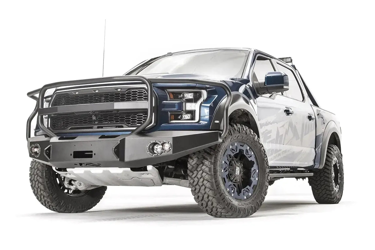 Fab Fours Premium Winch front bumper with full guard on a blue and gray wrapped Ford Raptor, front driver-side three-quarter view, showing the full grille guard, winch recess and round fog lights