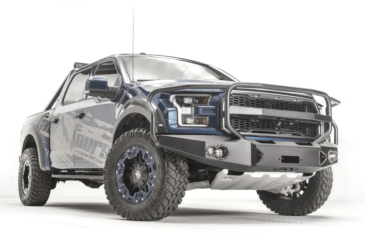 Fab Fours Premium Winch front bumper with full guard on a blue and gray wrapped Ford Raptor, front passenger-side three-quarter view, showing the full grille guard, winch recess and round fog lights