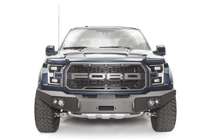 Fab Fours Premium Winch front bumper on a blue and gray wrapped Ford Raptor, straight-on front view, showing the center winch recess, round fog lights and shackle mounts