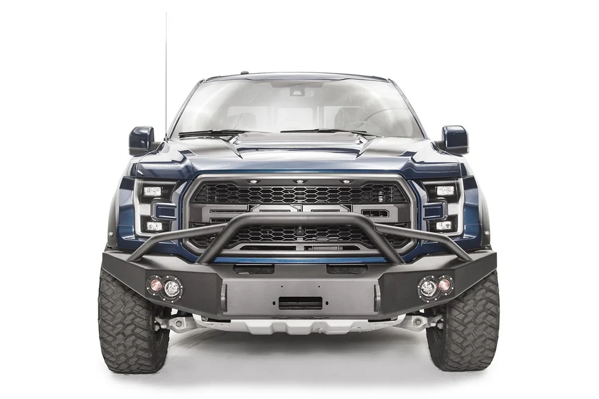 Fab Fours Premium Winch front bumper with pre-runner guard on a blue and gray wrapped Ford Raptor, straight-on front view, showing the pre-runner hoop, center winch recess and round fog lights