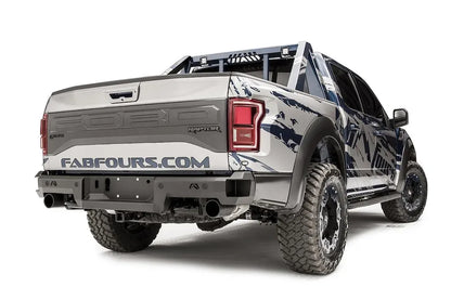Fab Fours Premium rear bumper on a silver and navy wrapped Ford Raptor, rear passenger-side three-quarter view, showing the logo cutouts, bumper end and chase rack