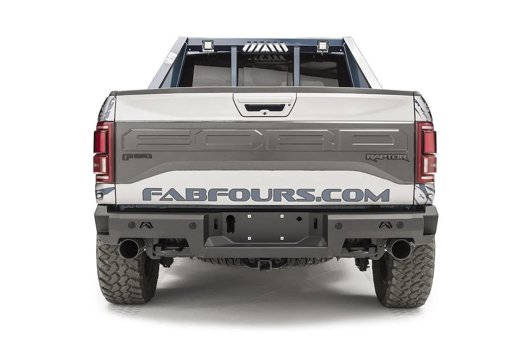 Fab Fours Premium rear bumper on a silver and navy wrapped Ford Raptor, straight-on rear view, showing the logo cutouts, center plate recess and exhaust openings