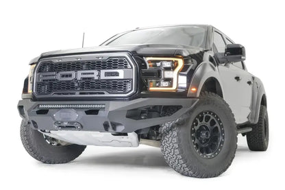 Fab Fours Matrix front bumper on a black Ford Raptor, front driver-side three-quarter view, showing the light bar, winch fairlead and skid plate