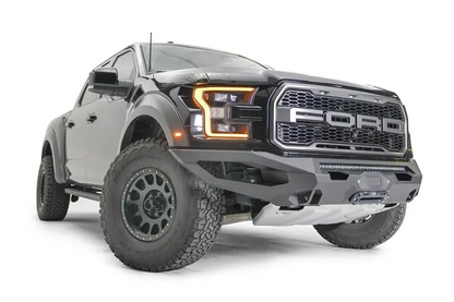 Fab Fours Matrix front bumper on a black Ford Raptor, front passenger-side three-quarter view, showing the light bar, winch fairlead and angled end caps