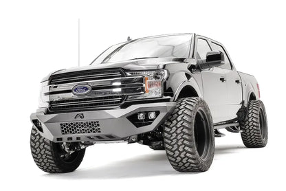 Fab Fours Vengeance front bumper on a black Ford F-150, front driver-side three-quarter view, showing the mesh center panel, cube light pods and skid plate