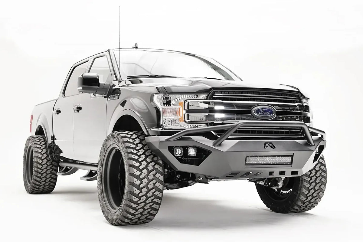Fab Fours Vengeance front bumper with pre-runner guard on a black Ford F-150, front passenger-side three-quarter view, showing the pre-runner hoop, light bar and cube light pods