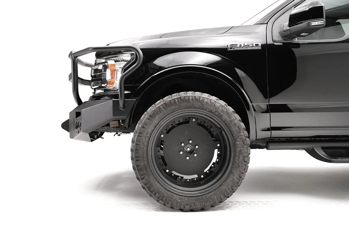 Fab Fours Premium Winch front bumper with full guard on a black Ford F-150, close-up of the front corner, showing the guard upright, bumper end and wheel clearance