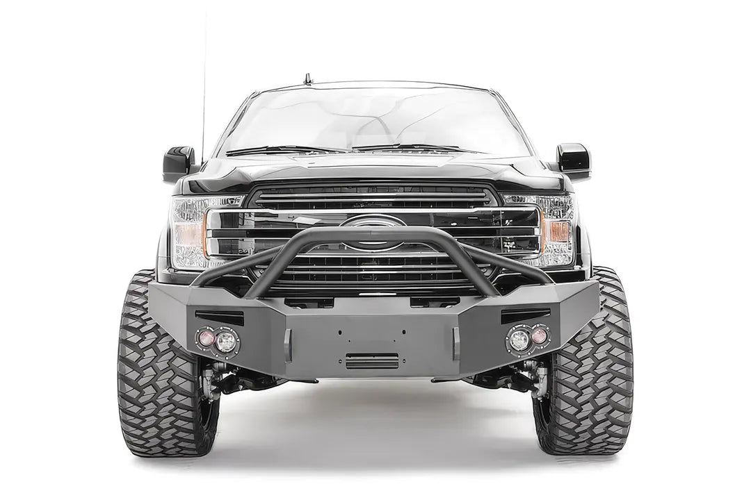 Fab Fours Premium Winch front bumper with pre-runner guard on a black Ford F-150, straight-on front view, showing the pre-runner hoop, center winch recess and round fog lights