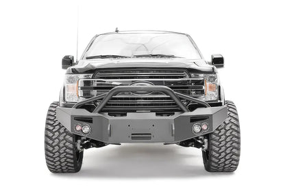 Fab Fours Premium Winch front bumper with pre-runner guard on a black Ford F-150, straight-on front view, showing the pre-runner hoop, center winch recess and round fog lights