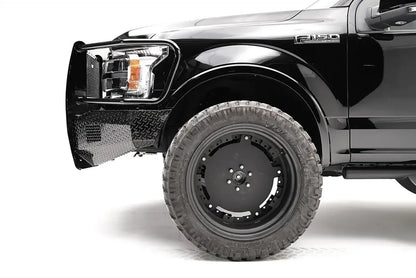 Fab Fours Black Steel front bumper with full guard on a black Ford F-150, close-up of the front corner, showing the guard upright, diamond-plate bumper end and wheel clearance