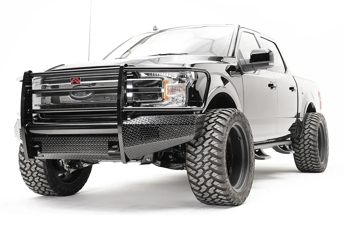 Fab Fours Black Steel front bumper with full guard on a black Ford F-150, front driver-side three-quarter view, showing the full grille guard, diamond-plate face and bumper wings