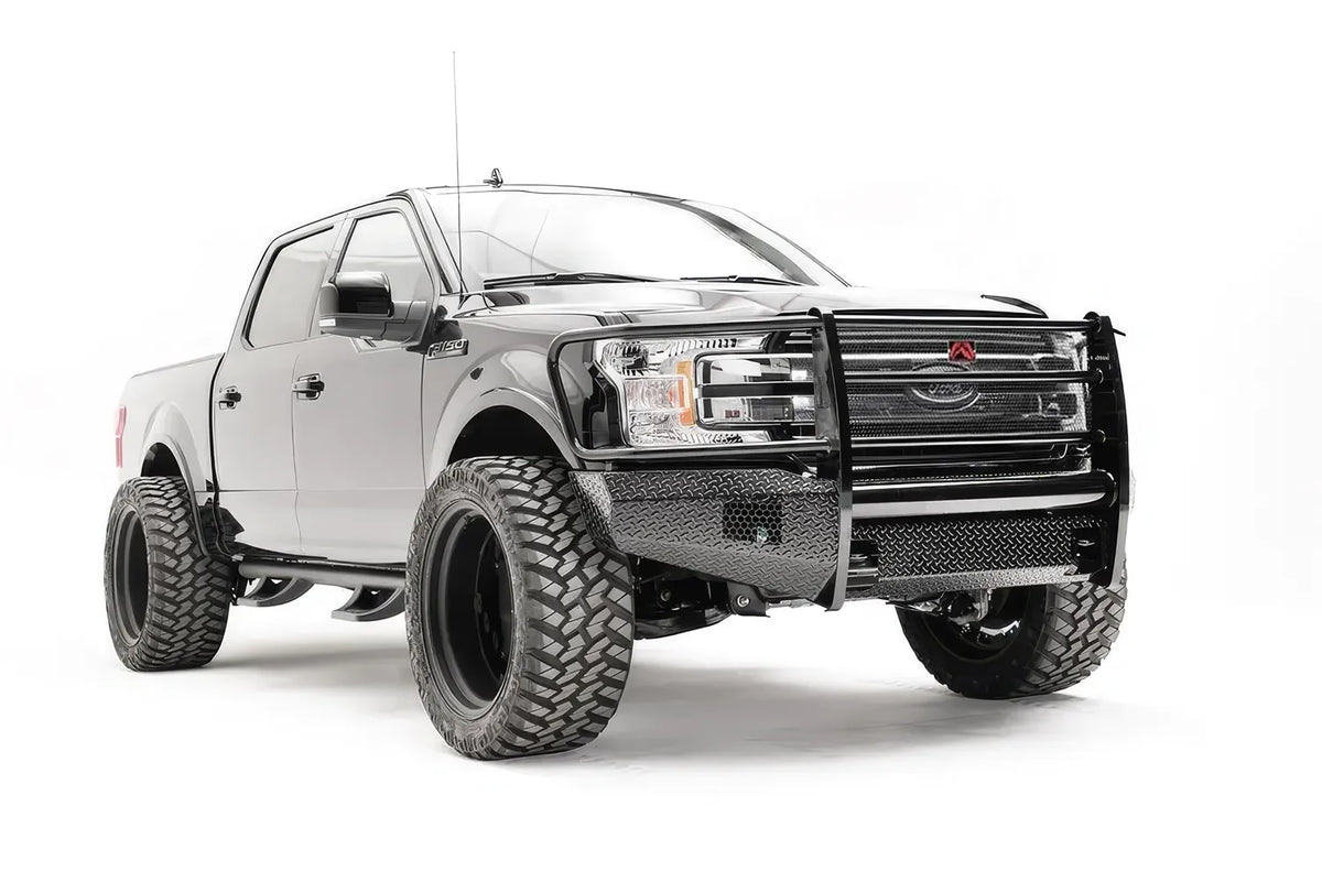 Fab Fours Black Steel front bumper with full guard on a black Ford F-150, front passenger-side three-quarter view, showing the full grille guard, diamond-plate face and bumper wings