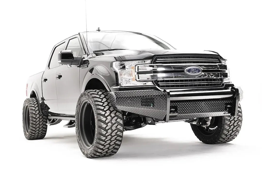 Fab Fours Black Steel front bumper on a black Ford F-150, front passenger-side three-quarter view, showing the diamond-plate face, tube top rail and bumper wings