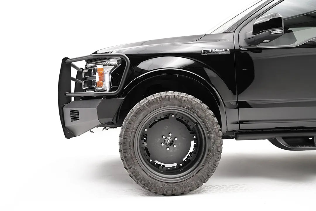 Fab Fours Black Steel Elite front bumper with full guard on a black Ford F-150, close-up of the front corner, showing the guard upright, bumper end and mesh vent