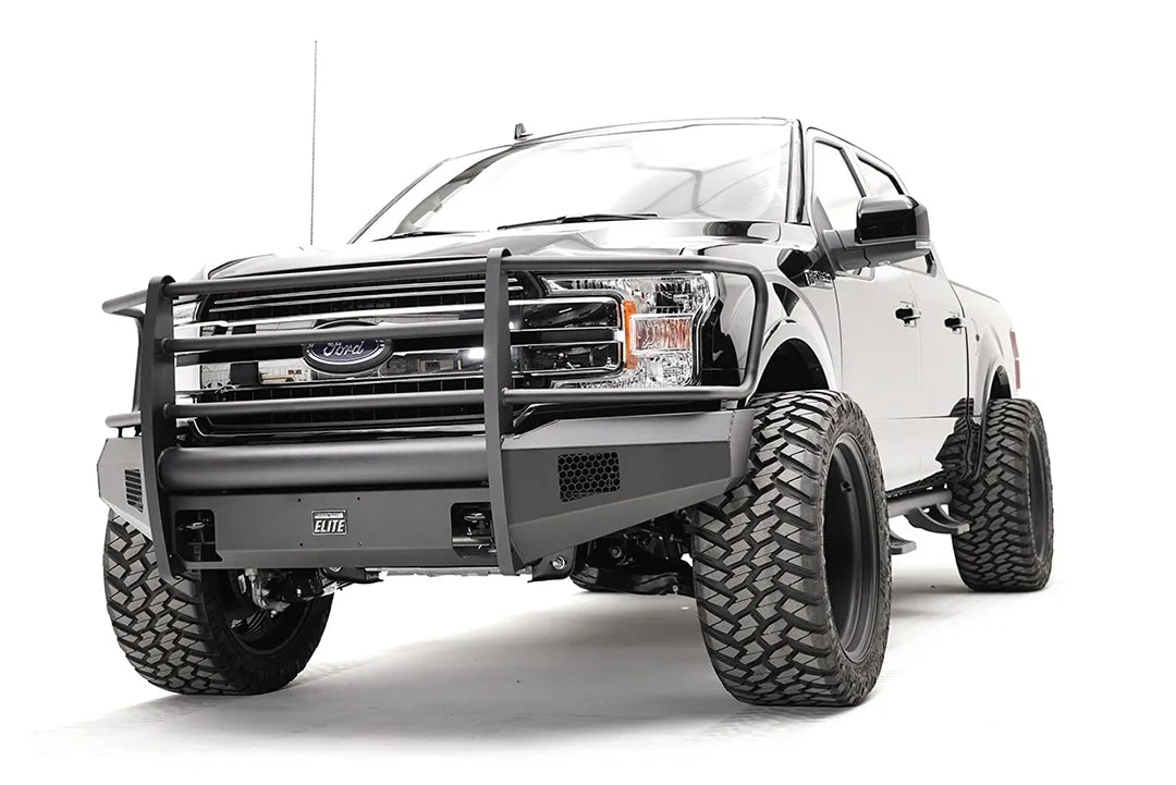 Fab Fours Black Steel Elite front bumper with full guard on a black Ford F-150, front driver-side three-quarter view, showing the full grille guard, smooth bumper face and mesh vents