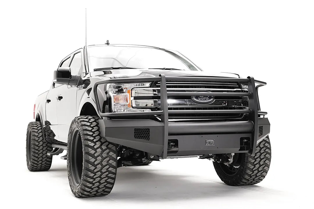 Fab Fours Black Steel Elite front bumper with full guard on a black Ford F-150, front passenger-side three-quarter view, showing the full grille guard, smooth bumper face and mesh vents