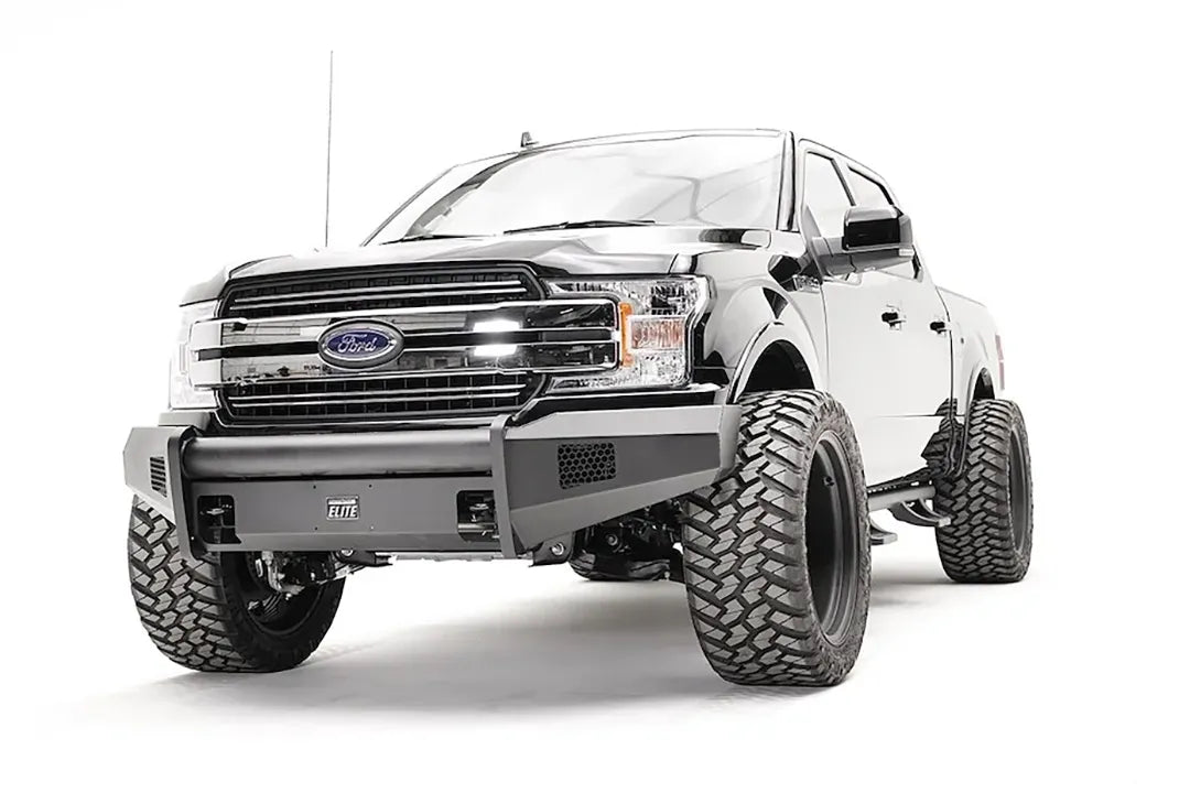 Fab Fours Black Steel Elite front bumper on a black Ford F-150, front driver-side three-quarter view, showing the smooth bumper face, mesh vents and wrapped ends