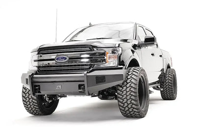 Fab Fours Black Steel Elite front bumper on a black Ford F-150, front driver-side three-quarter view, showing the smooth bumper face, mesh vents and wrapped ends