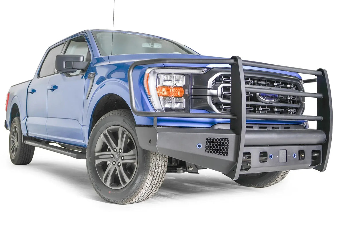 Fab Fours Black Steel Elite front bumper with full guard on a blue Ford F-150, front passenger-side three-quarter view, showing the full grille guard, mesh vent and bumper end