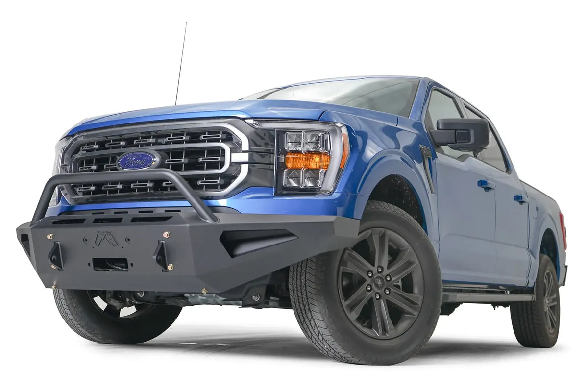 Fab Fours Red Steel front bumper with pre-runner guard on a blue Ford F-150, front driver-side three-quarter view, showing the pre-runner hoop, logo cutout and angled bumper wing