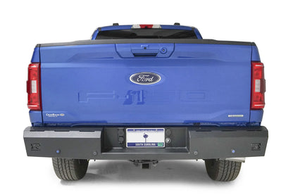 Fab Fours Red Steel rear bumper on a blue Ford F-150, straight-on rear view, showing the full-width bumper, sensor holes and corner light cutouts