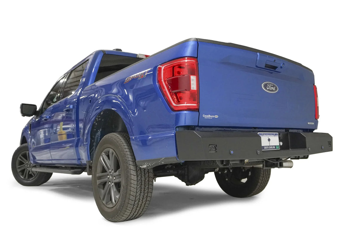 Fab Fours Red Steel rear bumper on a blue Ford F-150, rear driver-side three-quarter view, showing the bumper end, corner light cutout and sensor holes