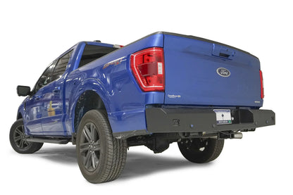 Fab Fours Red Steel rear bumper on a blue Ford F-150, rear driver-side three-quarter view, showing the bumper end, corner light cutout and sensor holes