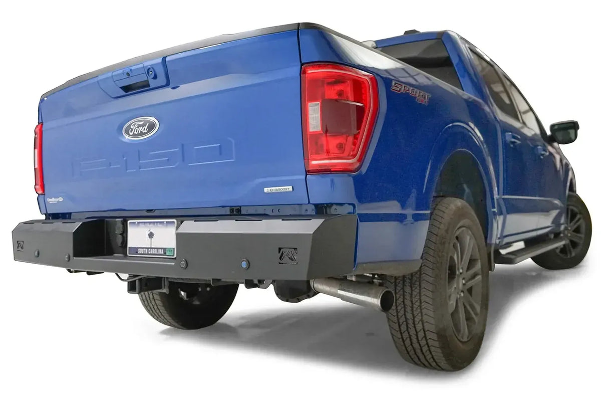 Fab Fours Red Steel rear bumper on a blue Ford F-150, rear passenger-side three-quarter view, showing the bumper end, corner light cutout and receiver hitch