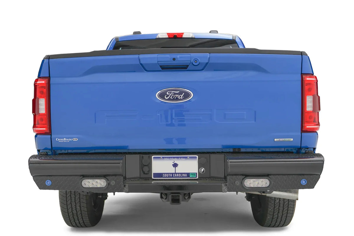 Fab Fours Black Steel rear bumper on a blue Ford F-150, straight-on rear view, showing the diamond-plate ends, rectangular lights and license plate mount