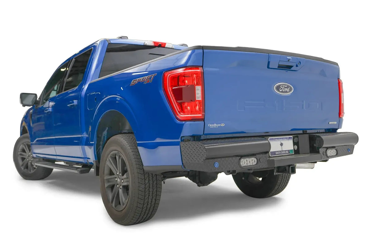 Fab Fours Black Steel rear bumper on a blue Ford F-150, rear driver-side three-quarter view, showing the diamond-plate end cap, rectangular light and receiver hitch