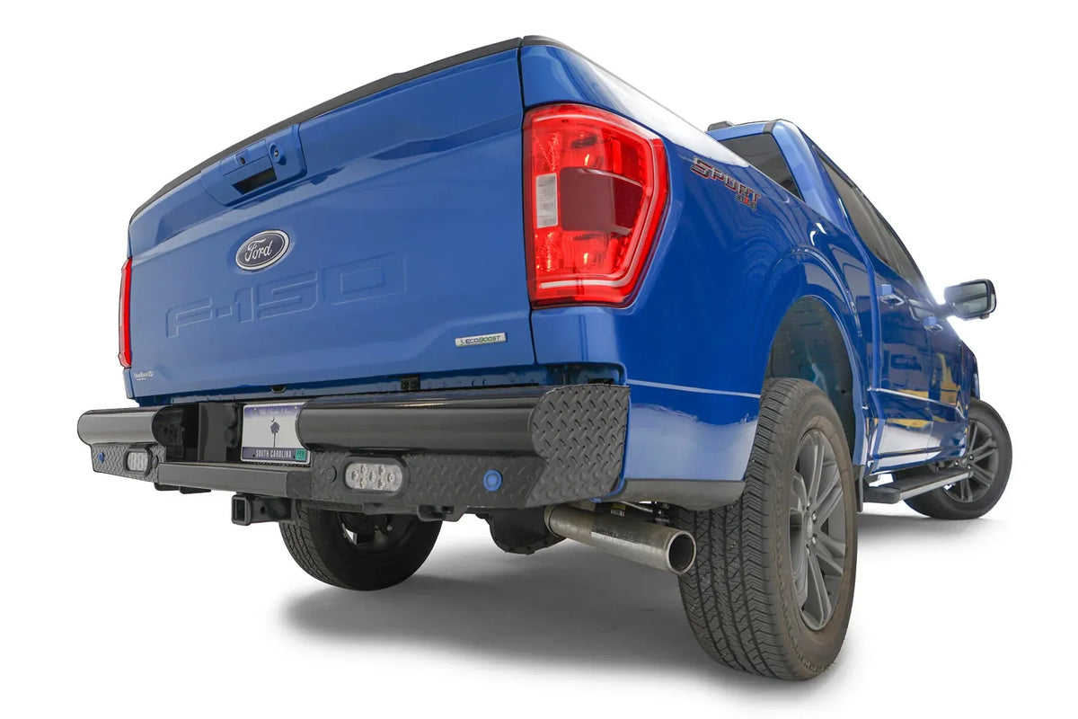 Fab Fours Black Steel rear bumper on a blue Ford F-150, rear passenger-side three-quarter view, showing the diamond-plate end cap and rectangular lights
