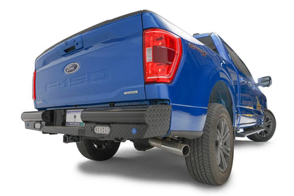Fab Fours Black Steel rear bumper on a blue Ford F-150, rear passenger-side three-quarter view, showing the diamond-plate end cap and rectangular lights