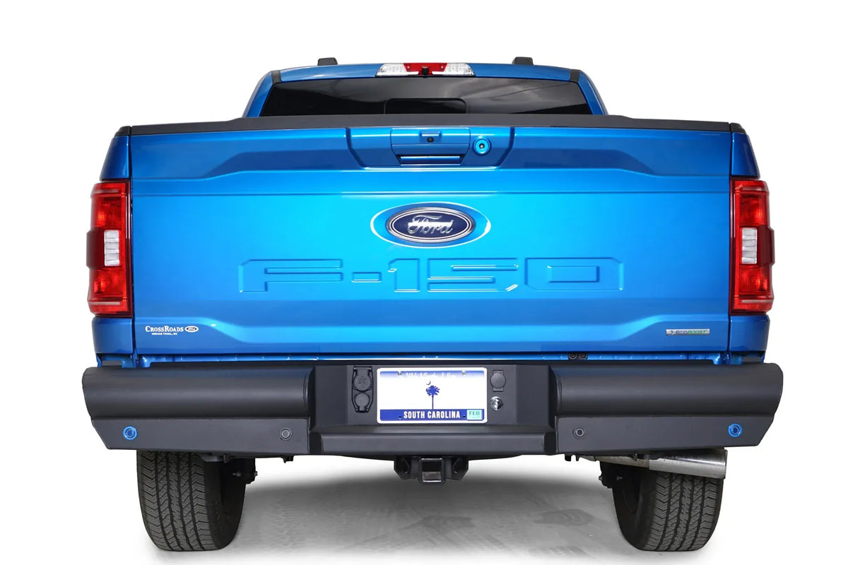 Fab Fours Black Steel Elite rear bumper on a blue Ford F-150, straight-on rear view, showing the smooth full-width bumper, sensor holes and license plate recess