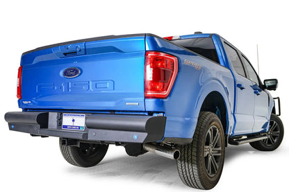 Fab Fours Black Steel Elite rear bumper on a blue Ford F-150, rear passenger-side three-quarter view, showing the wrapped bumper end and sensor holes