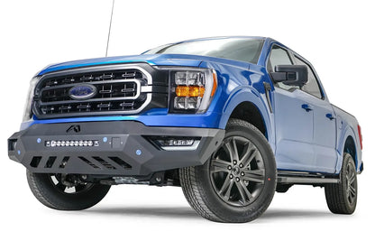 Fab Fours Vengeance front bumper on a blue Ford F-150, front driver-side three-quarter view, showing the light bar, angled end cap and skid plate cutouts
