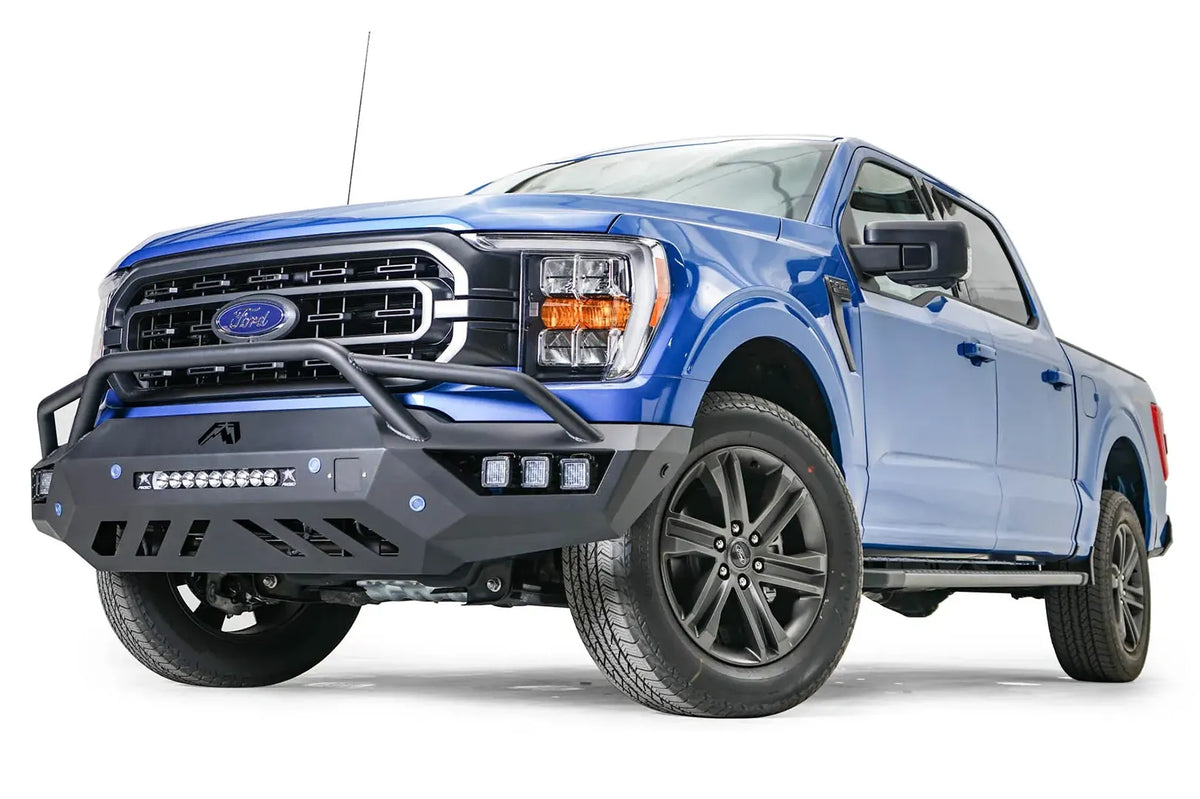Fab Fours Vengeance front bumper with pre-runner guard on a blue Ford F-150, front driver-side three-quarter view, showing the pre-runner hoop, light bar and cube light pods