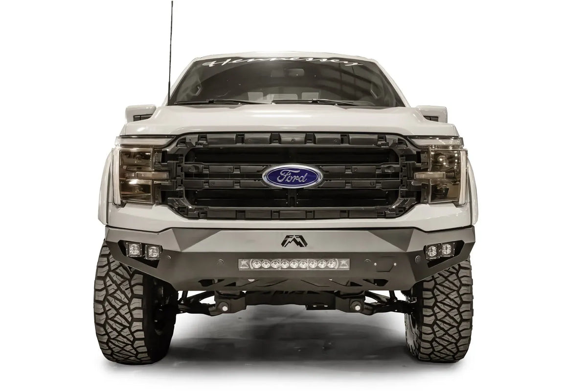 Fab Fours Vengeance front bumper on a white Ford F-150, straight-on front view, showing the center light bar, cube light pods and Fab Fours logo