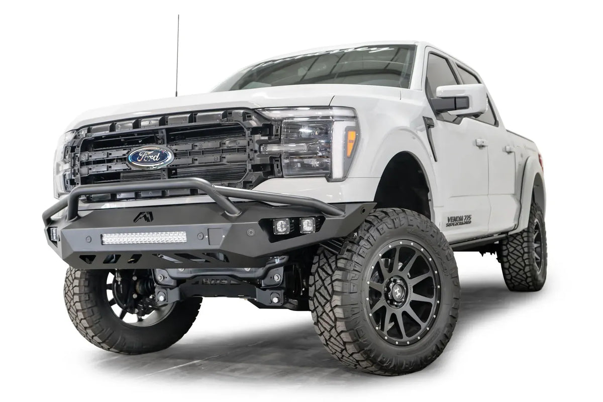 Fab Fours Vengeance front bumper with pre-runner guard on a white Ford F-150, front driver-side three-quarter view, showing the pre-runner hoop, light bar and cube light pods