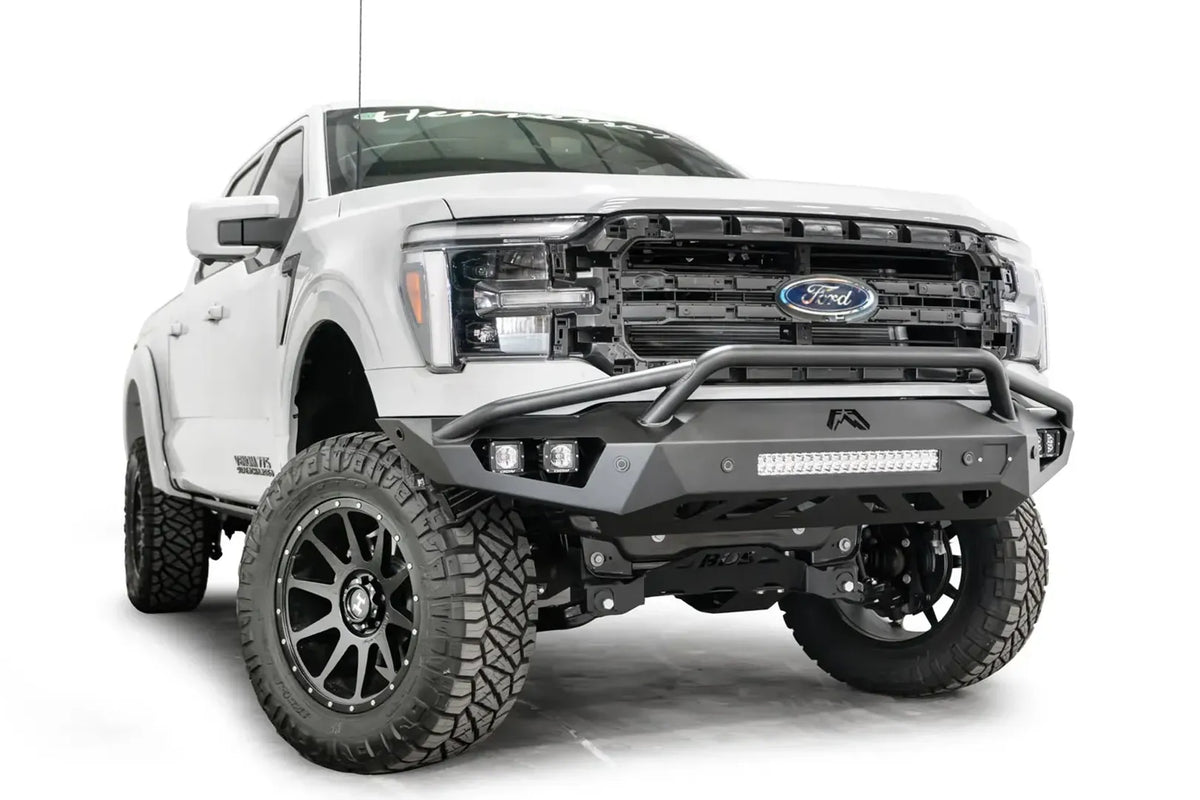 Fab Fours Vengeance front bumper with pre-runner guard on a white Ford F-150, front passenger-side three-quarter view, showing the pre-runner hoop, light bar and cube light pods