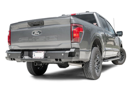Fab Fours Premium rear bumper on a gray Ford F-150, rear passenger side view, showing the sensor cutouts, the angled corner end caps and the recessed license plate mount