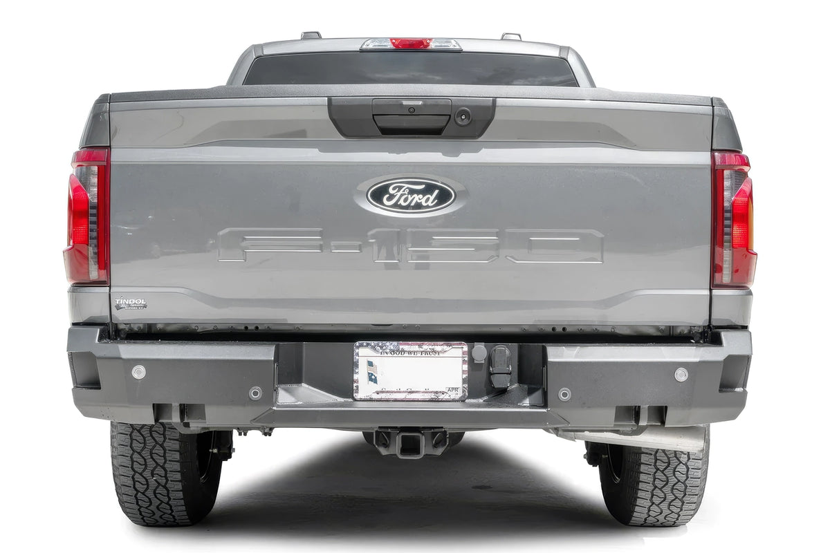 Fab Fours Premium rear bumper on a gray Ford F-150, straight-on rear view, showing the parking sensor cutouts, the center license plate recess and the hitch receiver access
