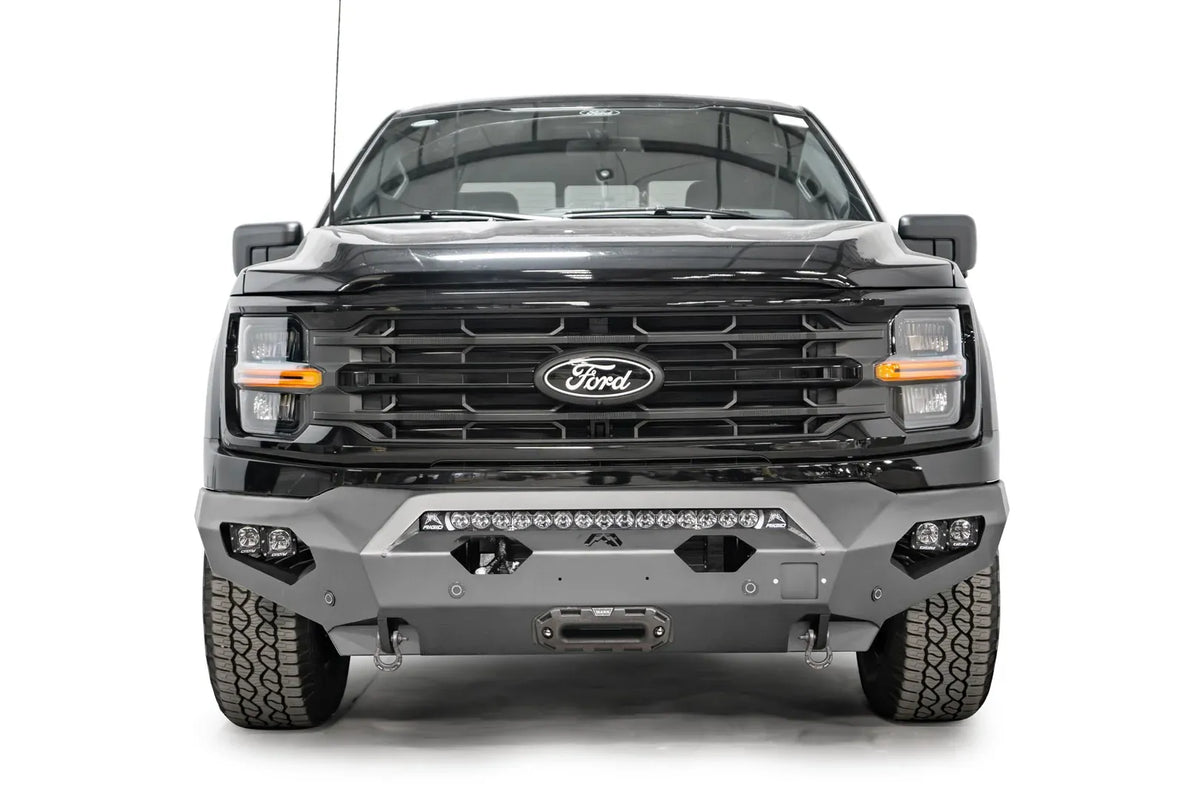 Fab Fours Matrix front bumper on a black Ford F-150, straight-on front view, showing the center light bar, winch fairlead and cube light pods