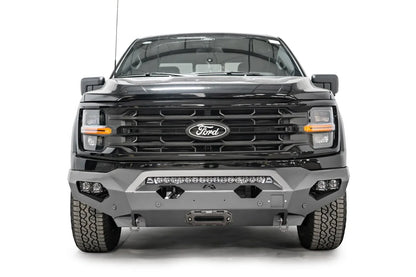 Fab Fours Matrix front bumper on a black Ford F-150, straight-on front view, showing the center light bar, winch fairlead and cube light pods