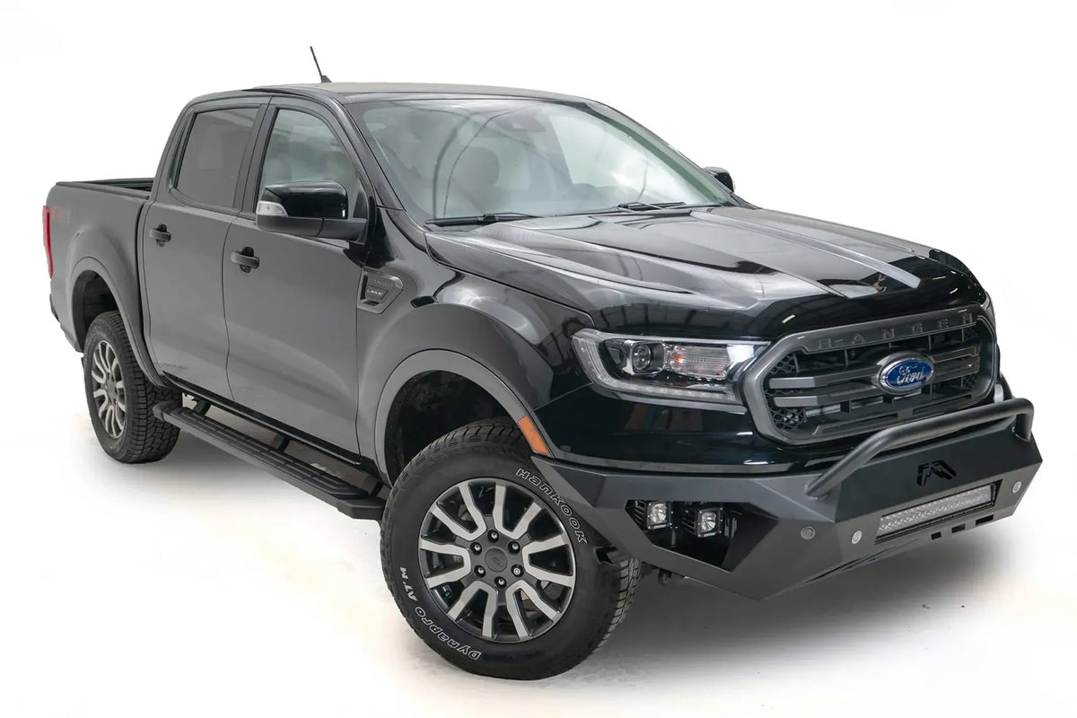 Fab Fours Vengeance front bumper with pre-runner guard on a black Ford Ranger, front passenger-side three-quarter view, showing the pre-runner hoop, light bar and cube light pods