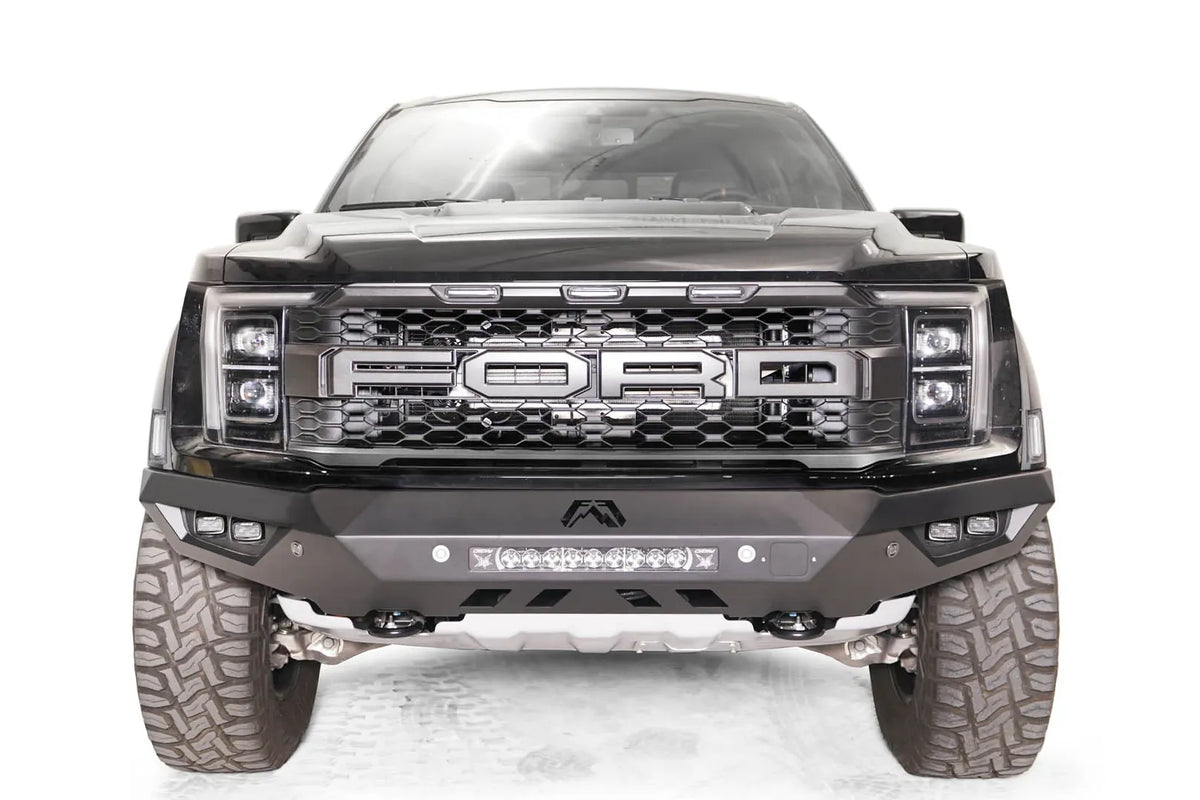 Fab Fours Vengeance front bumper on a black Ford Raptor, straight-on front view, showing the center light bar, cube light pods and skid plate
