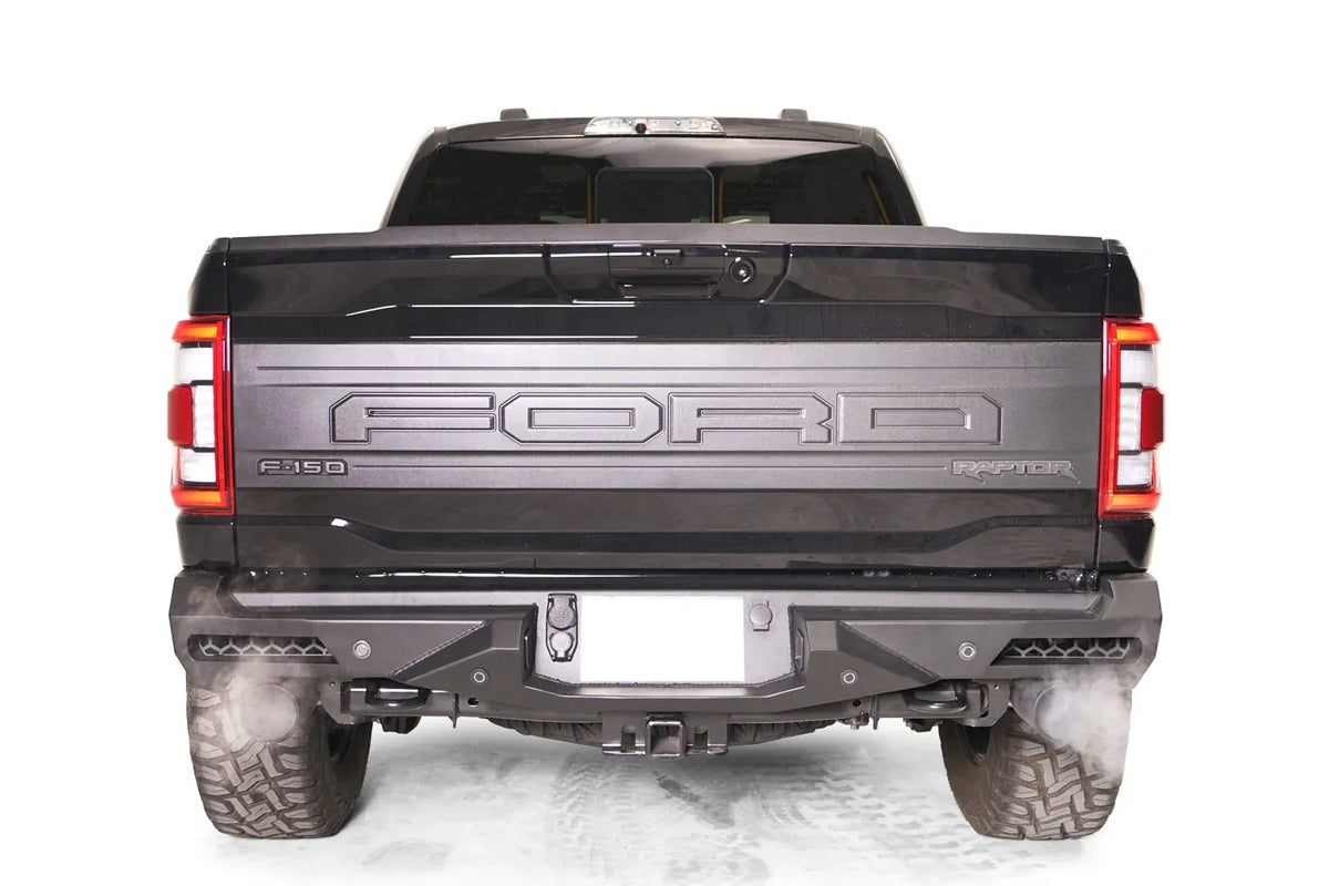 Fab Fours Vengeance rear bumper on a dark gray Ford F-150 Raptor, straight-on rear view, showing the full-width bumper, integrated corner lights and center hitch receiver opening