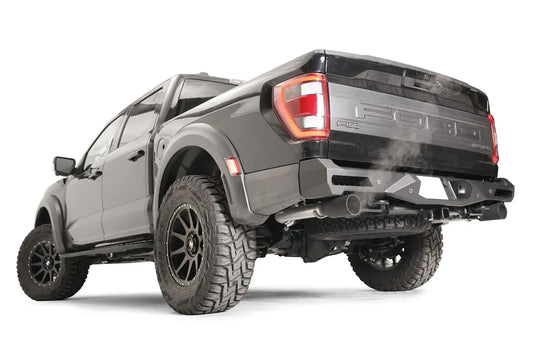Fab Fours Vengeance rear bumper on a dark gray Ford F-150 Raptor, rear driver-side three-quarter view, showing the angular bumper end cap, corner light and exhaust clearance